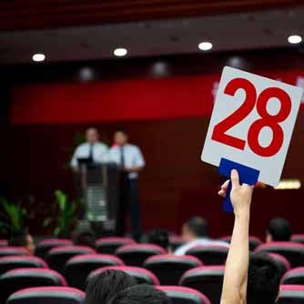 An audience member holds up an auction number while bidding at an auction.